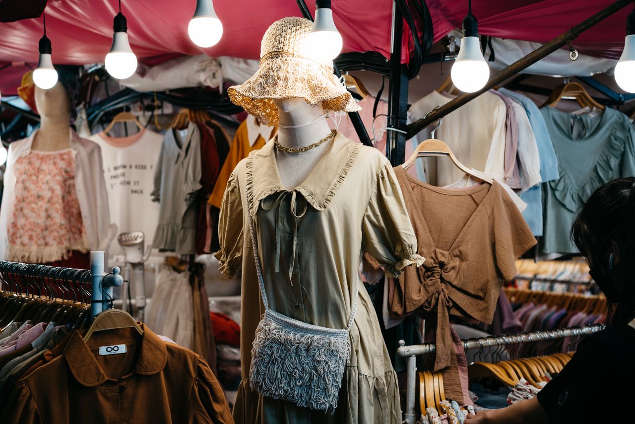A bustling street market showcasing trendy, diverse clothing under vibrant lighting.