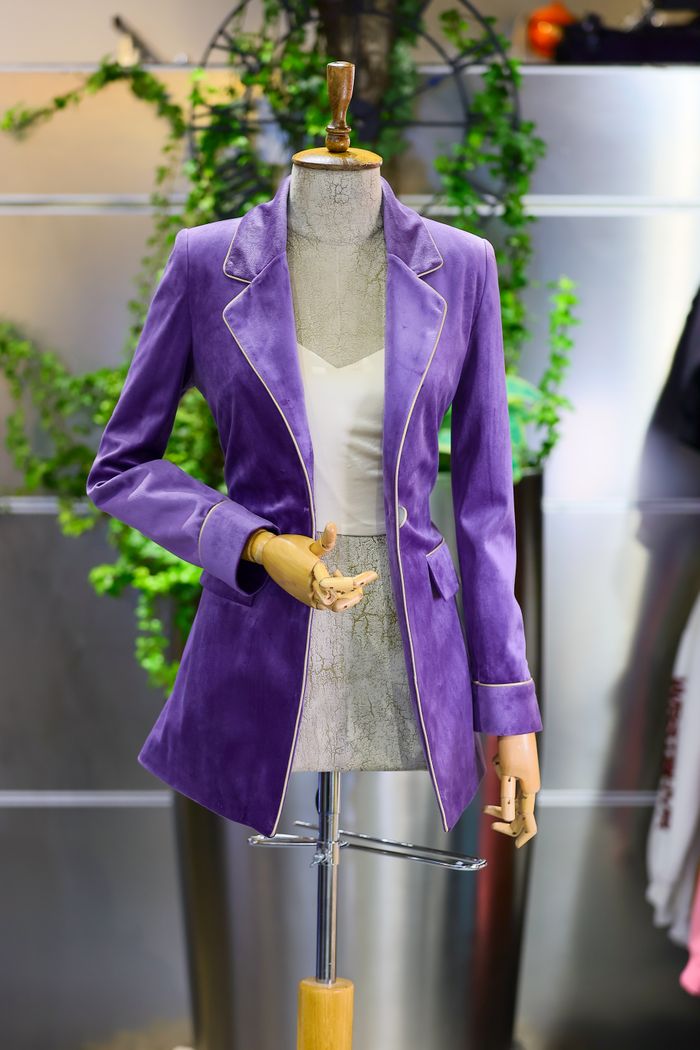 Elegant purple velvet jacket displayed on a mannequin in a stylish boutique setting.